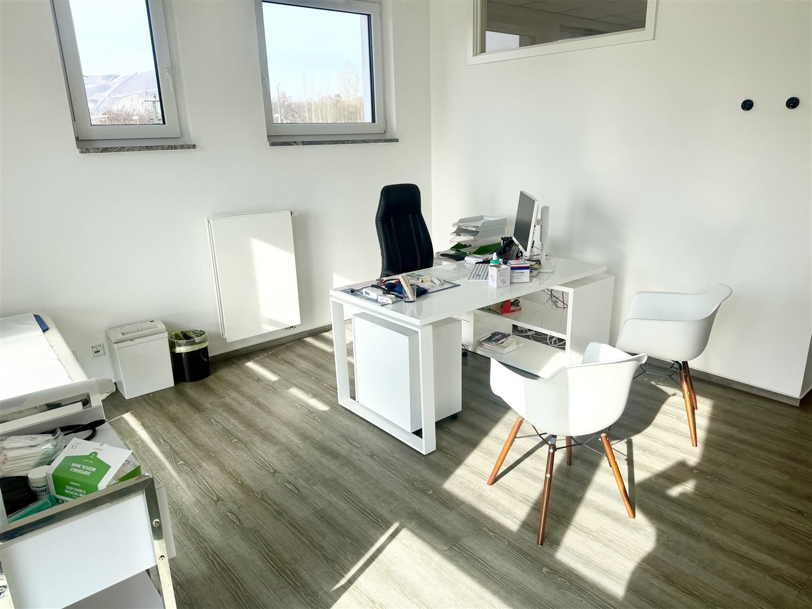 Helles Sprechzimmer mit Schreibtisch und Untersuchungsliege