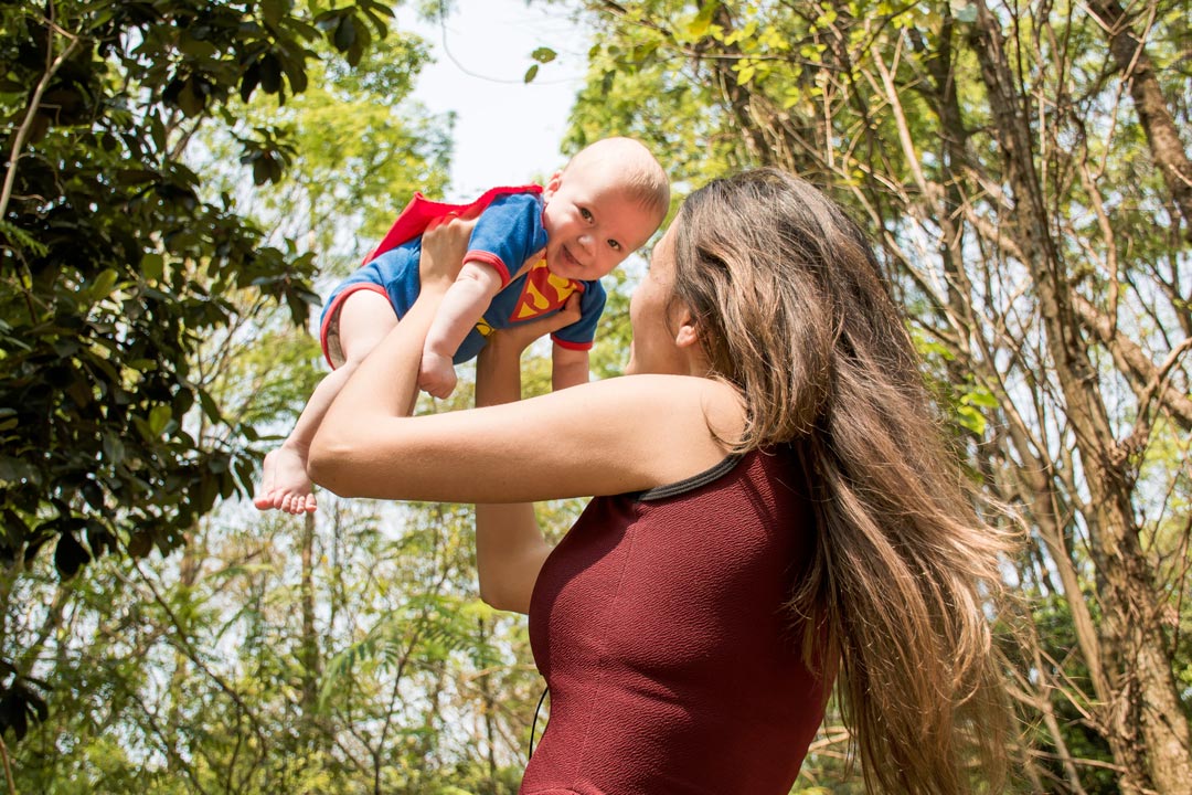 Mutter hebt lachend ihr Baby in die Luft